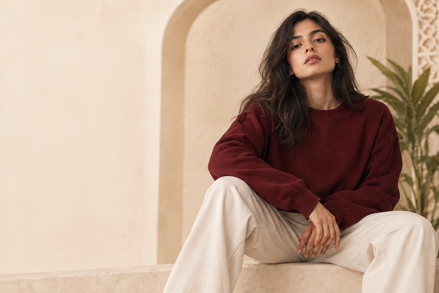 Woman in an oversized burgundy sweatshirt and wide-leg cream trousers
